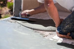 Concrete floor repair by worker laying down new concrete.